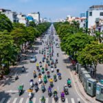 Đại lộ đô thị với dòng xe máy điện và tủ sạc ven đường, giao thông xanh tại thành phố đang phát triển