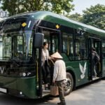 Xe buýt điện VinFast EB8 màu xanh Hanoibus mở cửa sàn thấp đón khách tại một điểm dừng ở Hà Nội