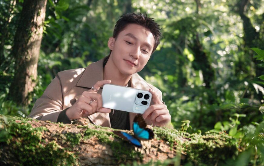 Sơn Tùng M-TP cầm chiếc OPPO Find X10 màu trắng chụp một con bướm xanh đậu trên thân cây phủ rêu trong rừng