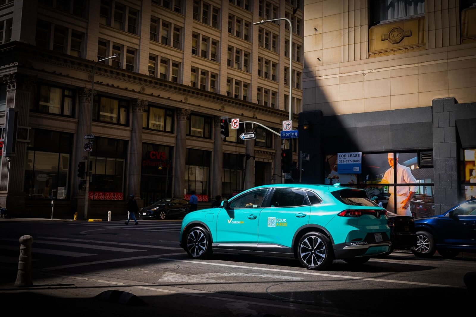 Xe taxi điện VinFast VF 8 màu xanh cyan của Green SM qua ngã tư đường Spring tại Los Angeles