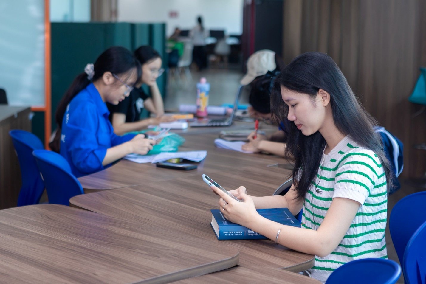 Nhóm bạn trẻ sử dụng điện thoại di động trong không gian học tập chung