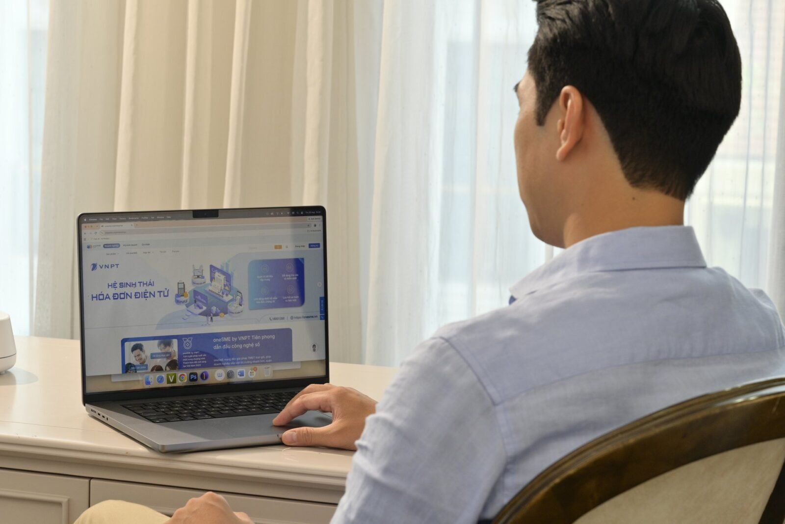 Người dùng ngồi tại bàn làm việc, mở laptop hiển thị trang hệ sinh thái hóa đơn điện tử của VNPT